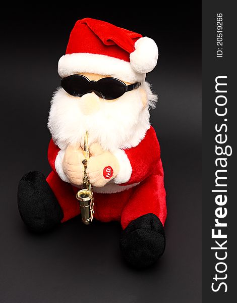 Soft toy Santa Claus wearing shades and playing saxophone on black background