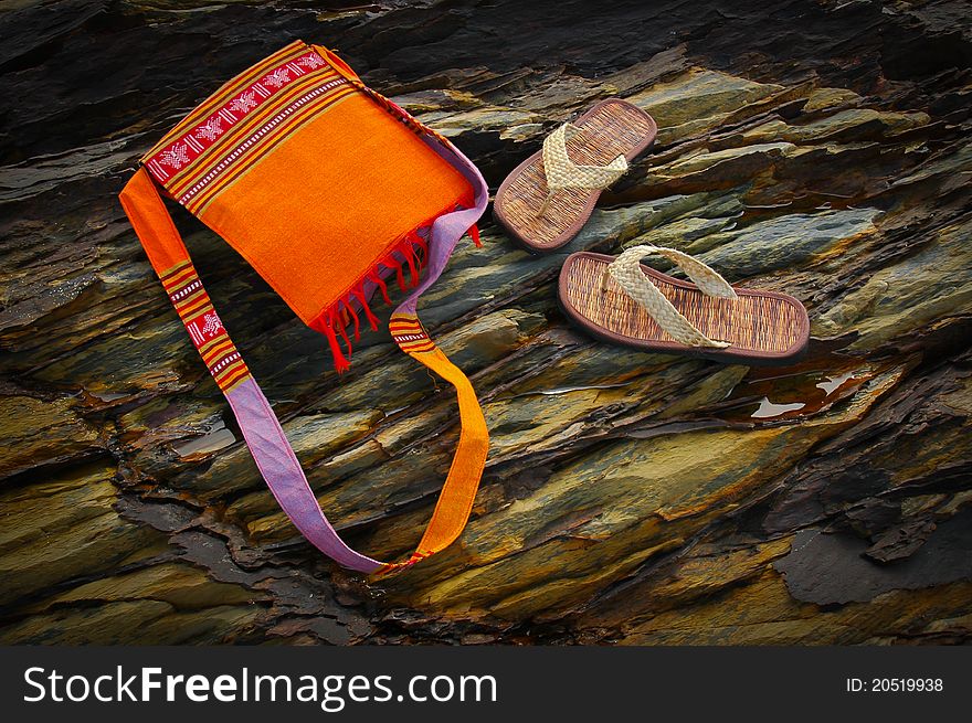 Flip flop and bag on the rock of the beach