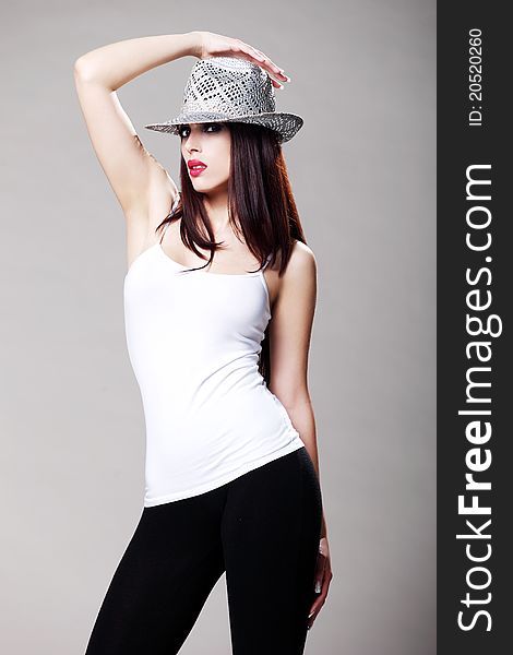 Attractive brunette in a white t shirt and black tights wearing a hat. Attractive brunette in a white t shirt and black tights wearing a hat