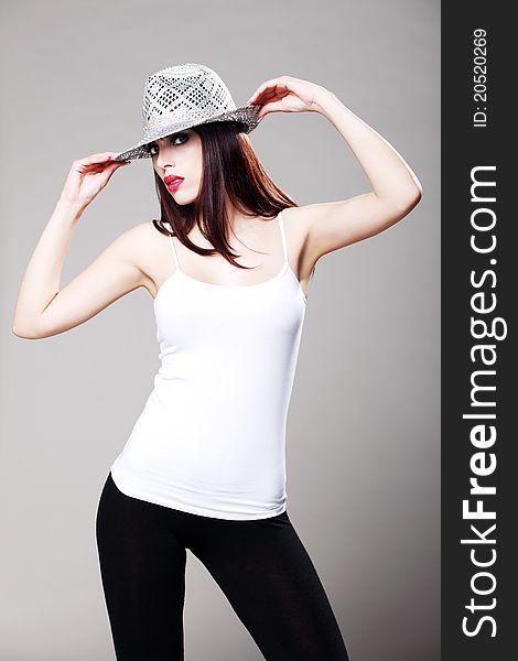 Attractive brunette in a white t shirt and black tights wearing a hat. Attractive brunette in a white t shirt and black tights wearing a hat