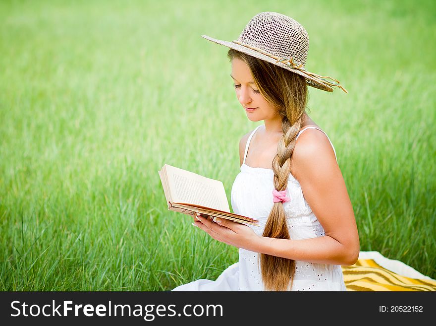 Young beautiful girl with book in nature in hat. Young beautiful girl with book in nature in hat