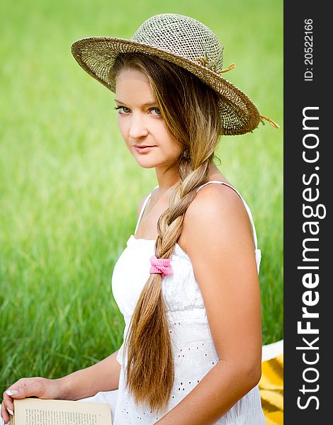 Young beautiful girl with book in nature in hat. Young beautiful girl with book in nature in hat