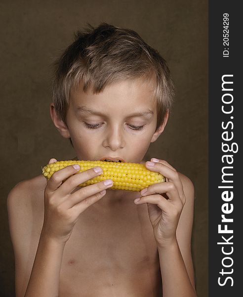 The boy with appetite eats the boiled corn.