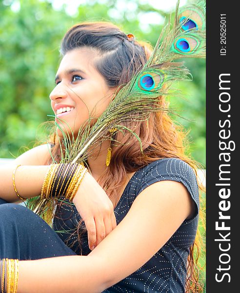 Young Pakistani model posing with traditional peacock feathers and gold ornaments. Young Pakistani model posing with traditional peacock feathers and gold ornaments