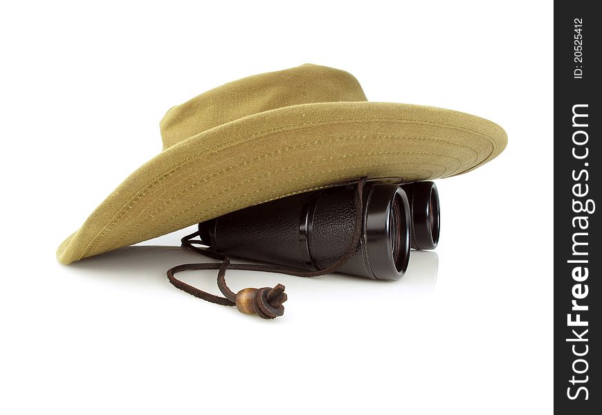 Old hikers hat with a pair of black binoculars on a white background. Old hikers hat with a pair of black binoculars on a white background