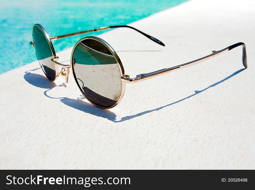 Black round sun glasses on pool in summer day