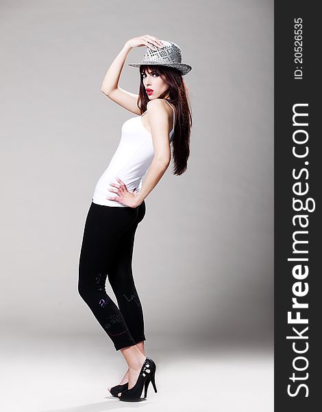 Attractive brunette in a white t shirt and black tights wearing a hat. Attractive brunette in a white t shirt and black tights wearing a hat