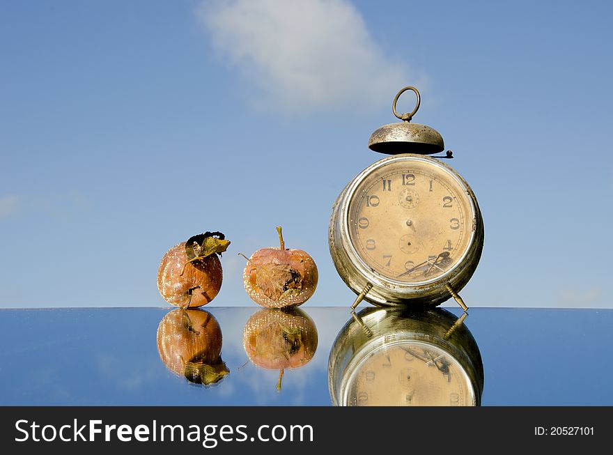 Vintage clock and rotten apples on mirror