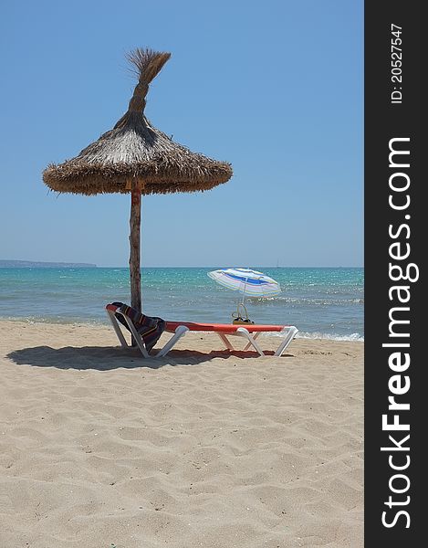 A sunbed under a parasol at the Palma bay beach. A sunbed under a parasol at the Palma bay beach.