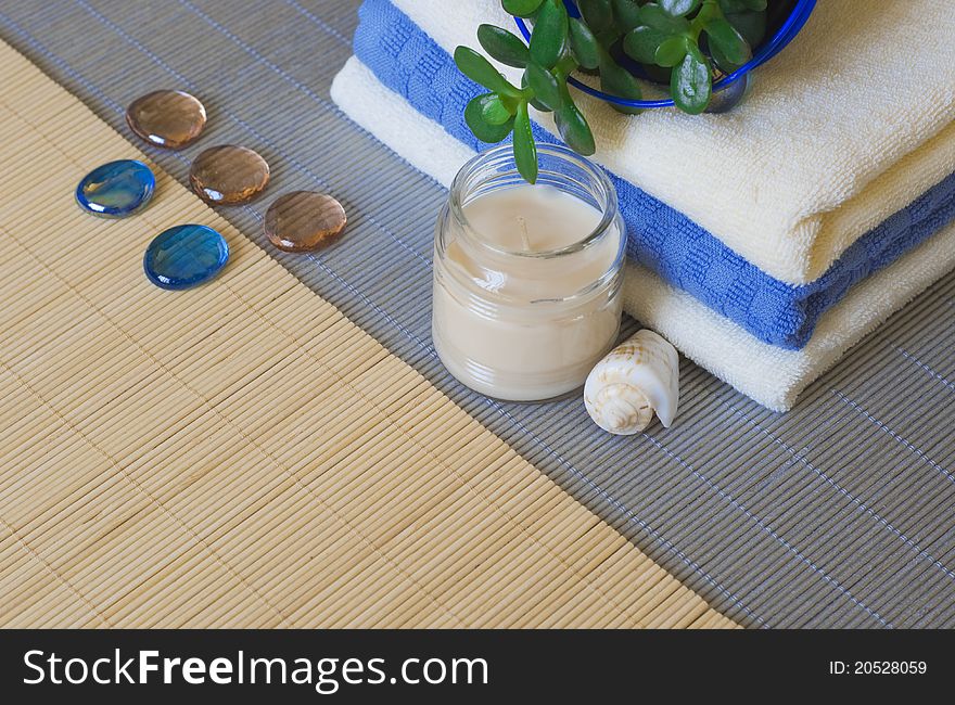 Towels and candles on a woven mat (with focus on candle and shell). Towels and candles on a woven mat (with focus on candle and shell)