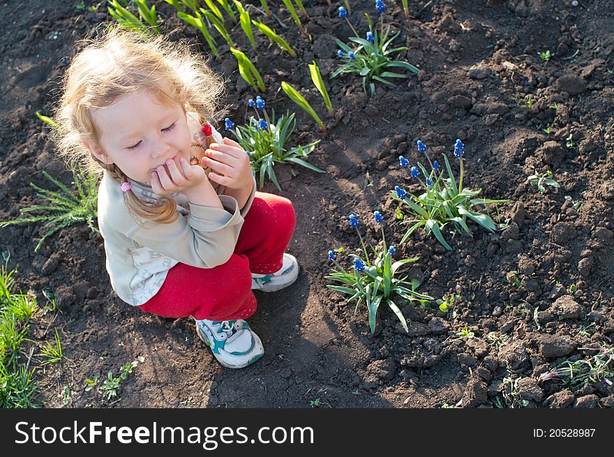 Carefree little girl sitting on a bed of flowers