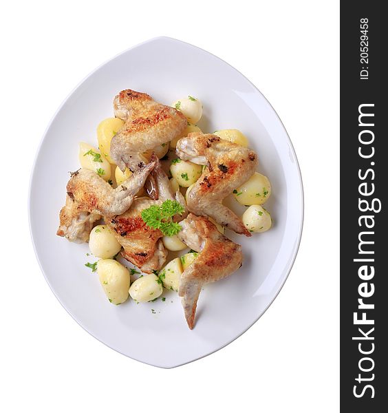 Roasted chicken wings and potatoes - overhead, cut out on white