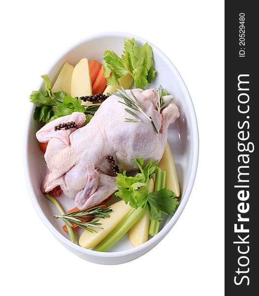 Raw chicken and vegetables in a casserole dish - cut out on white