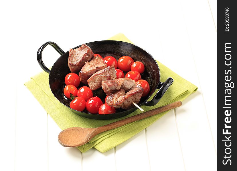 Pork kebab and cherry tomatoes in a pan. Pork kebab and cherry tomatoes in a pan