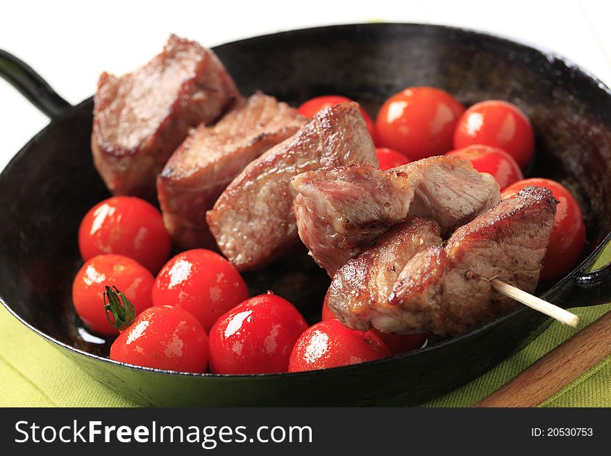 Pork kebab and cherry tomatoes in a pan. Pork kebab and cherry tomatoes in a pan