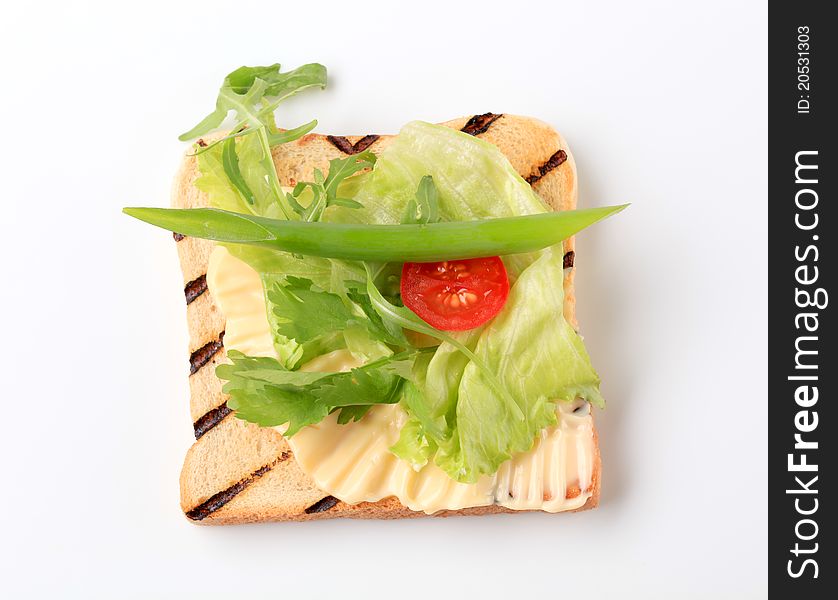 Slice of toasted bread with butter and fresh vegetables. Slice of toasted bread with butter and fresh vegetables