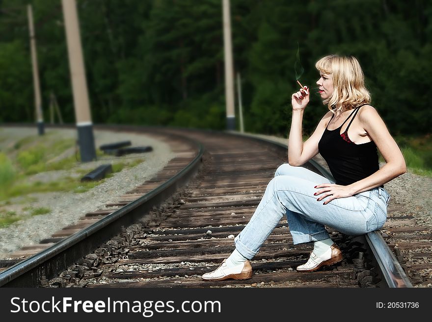 Sexy woman seating on railway and smoking cigaret