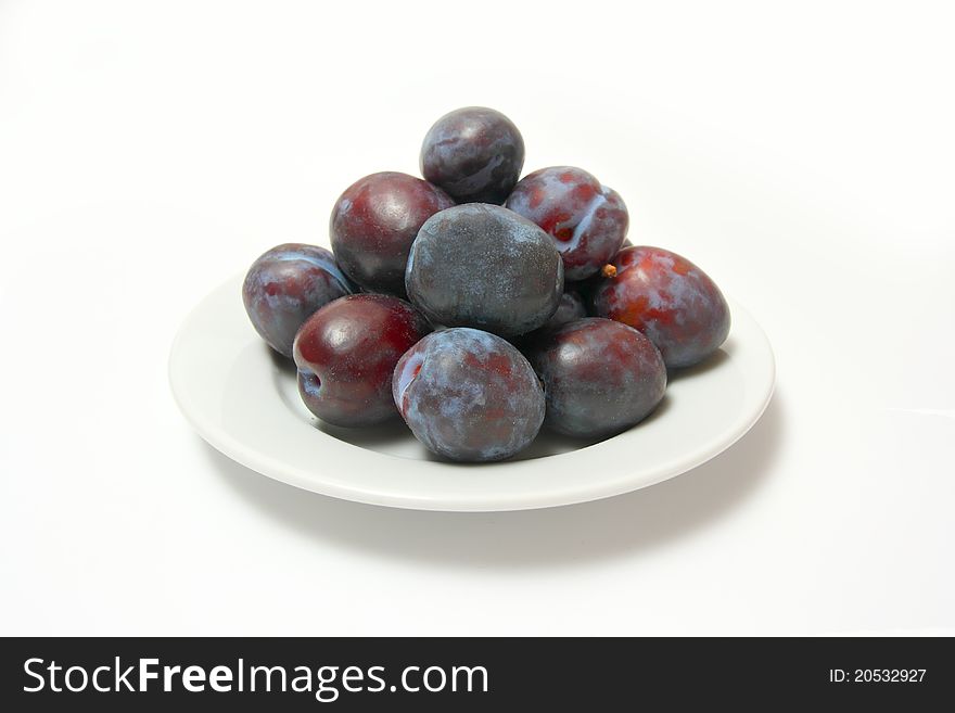 Ripe plums on porcelain plate