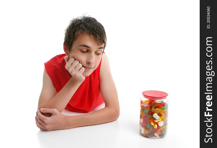 A boy ponders whether to open a jar of assorted confectionery.  White background. A boy ponders whether to open a jar of assorted confectionery.  White background.