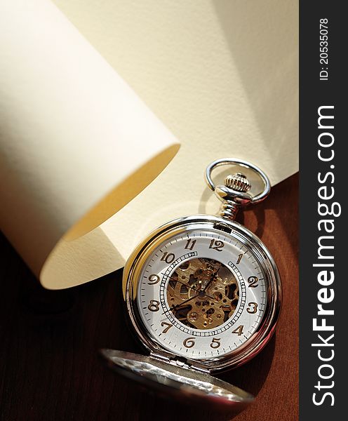 Closeup of nice pocket watch with open lid lying on blank scroll. Closeup of nice pocket watch with open lid lying on blank scroll