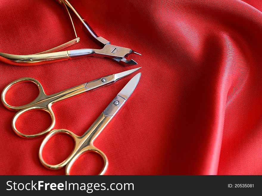 Modern golden manicure or pedicure set on red silk background. Modern golden manicure or pedicure set on red silk background