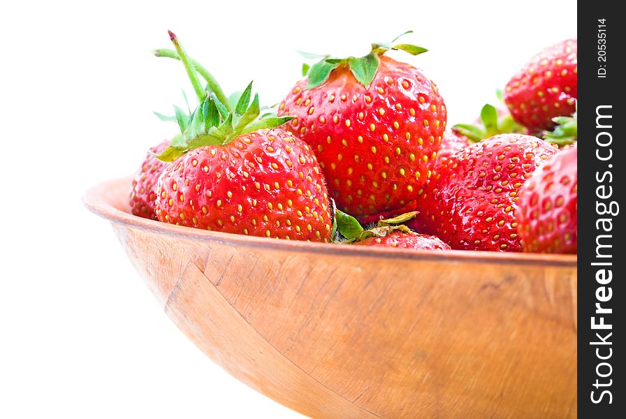 Mature red strawberry  lying in a wooden bowl (isolated)