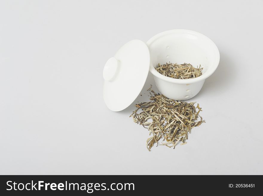 Dried jasmine tea to be used for tea with ceramic strainer on a grey background. Dried jasmine tea to be used for tea with ceramic strainer on a grey background