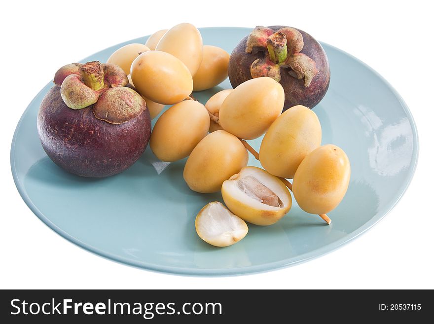 Fresh dates and two mangosteen on a blue plate, isolated against a white background. Fresh dates and two mangosteen on a blue plate, isolated against a white background