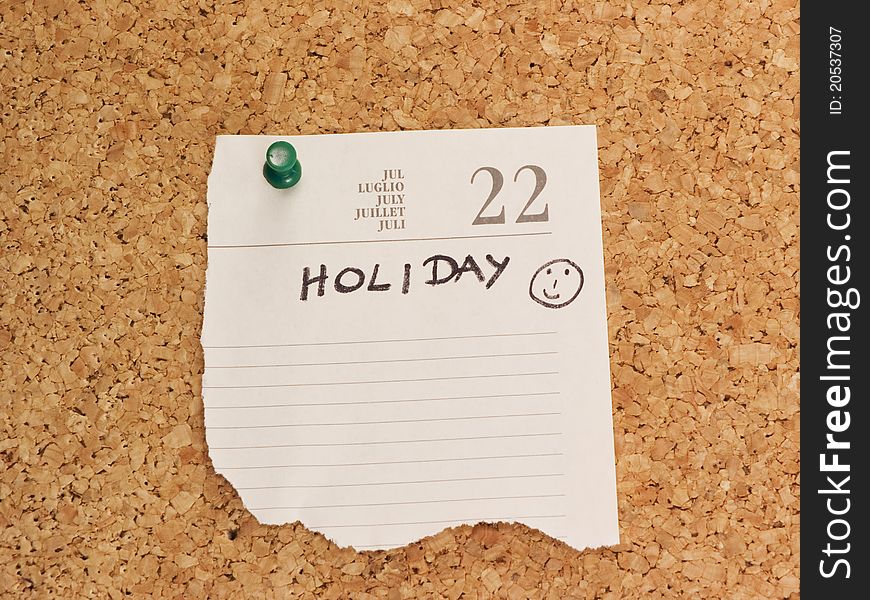 Holiday reminder on cork board with green push pin