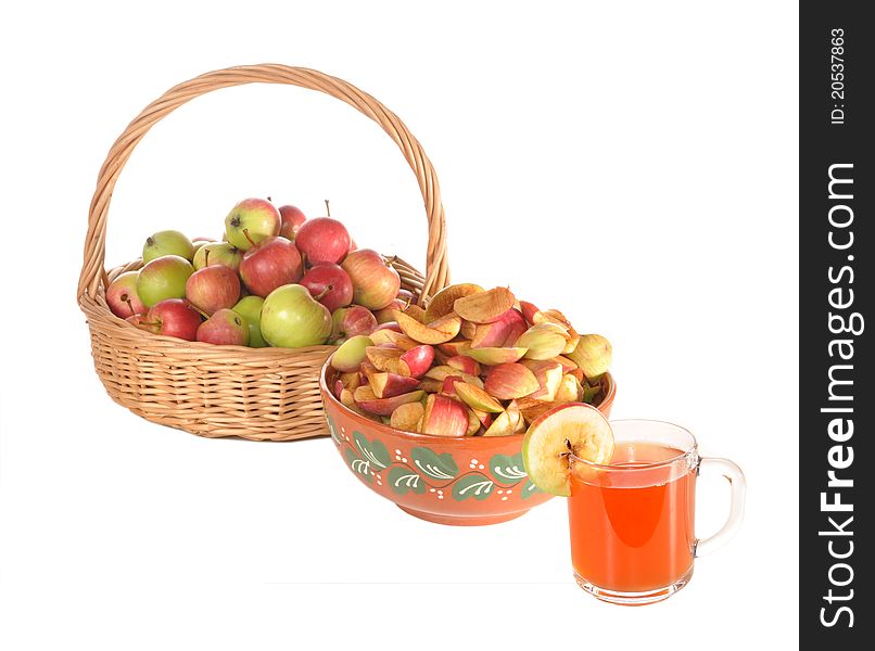 Apples lie in a basket, slices of apples in a ceramic bowl and a glass of apple juice stand on a table. Apples lie in a basket, slices of apples in a ceramic bowl and a glass of apple juice stand on a table