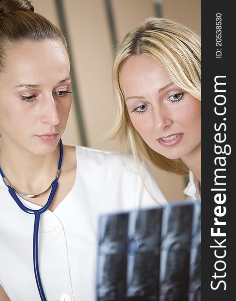 Two women doctors examining film scans of patient spine. Two women doctors examining film scans of patient spine.