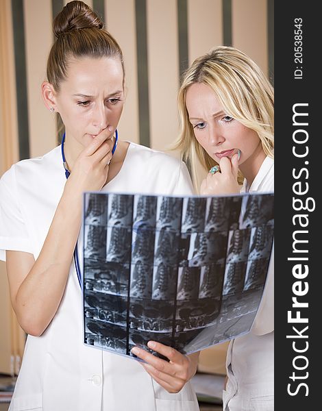 Women doctors reading radiology scans of patient spine. Women doctors reading radiology scans of patient spine