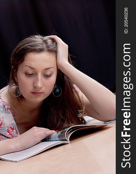 Girl reading a magazine on the floor, studio photography