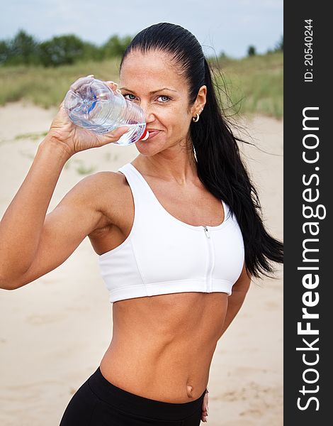 Young woman drinking water after fitness exercise. Young woman drinking water after fitness exercise
