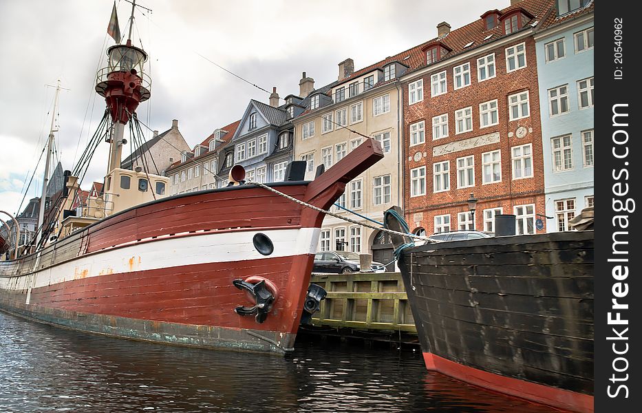 Some boats lying in the water next to houses in Copenhagen, Denmark