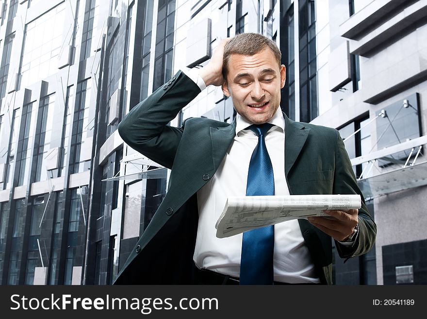 Young businessman reading a daily newspaper and holding his head. Young businessman reading a daily newspaper and holding his head