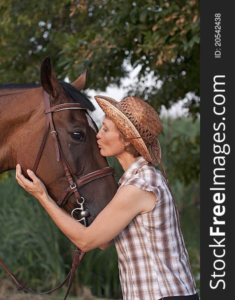 Woman in hat kissing the horse. Close-up portrate