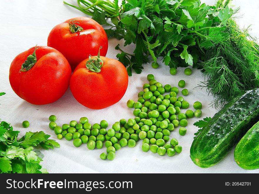 Fresh appetizing vegetables on table, red tomatoes, spring peas, parsley and cucumber. Fresh appetizing vegetables on table, red tomatoes, spring peas, parsley and cucumber