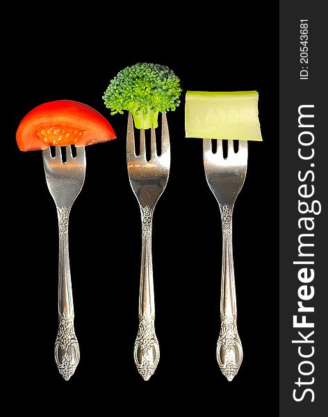 Forks with tomato, broccoli and celery on a black background. Forks with tomato, broccoli and celery on a black background