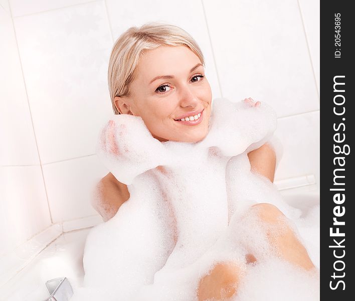 Beautiful young blond woman taking a relaxing bath with foam. Beautiful young blond woman taking a relaxing bath with foam