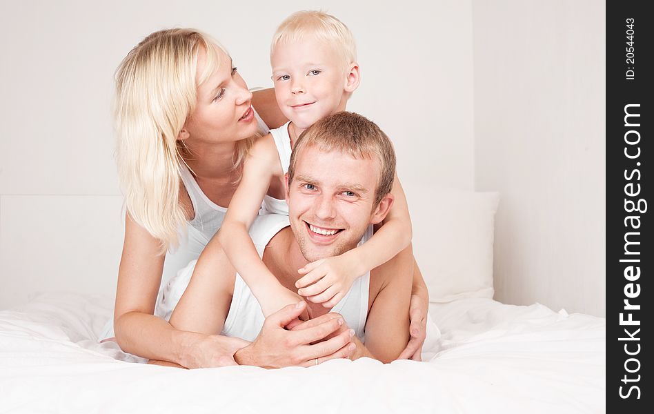 Happy family; mother ,father and their son on the bed at home. Happy family; mother ,father and their son on the bed at home