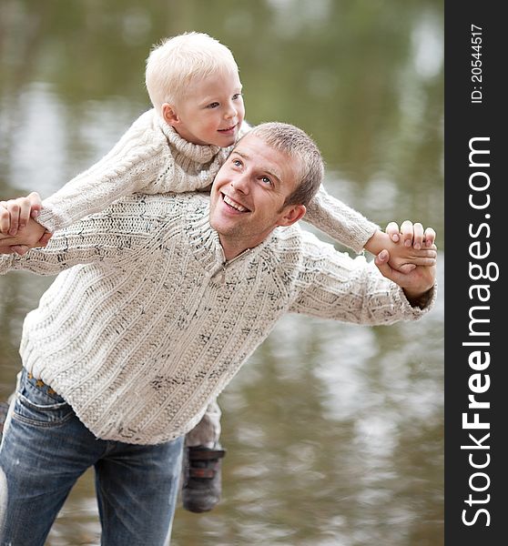 Happy  family; young father and his five year old son near the lake outdoor on a summer day (focus on the men). Happy  family; young father and his five year old son near the lake outdoor on a summer day (focus on the men)
