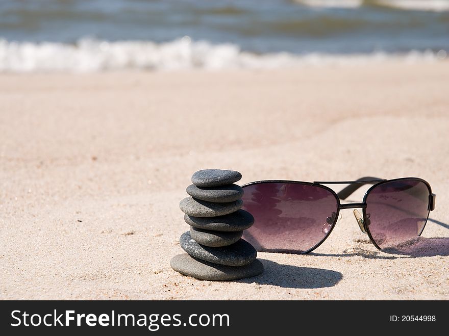 Pebble stack and sunglasse on the seashore