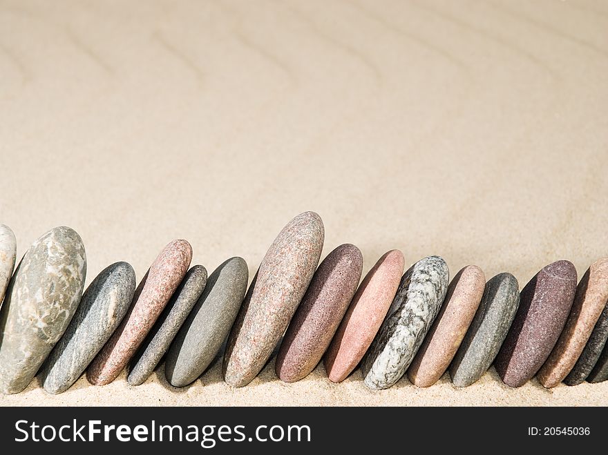 Row of flat stones on sand background. Row of flat stones on sand background