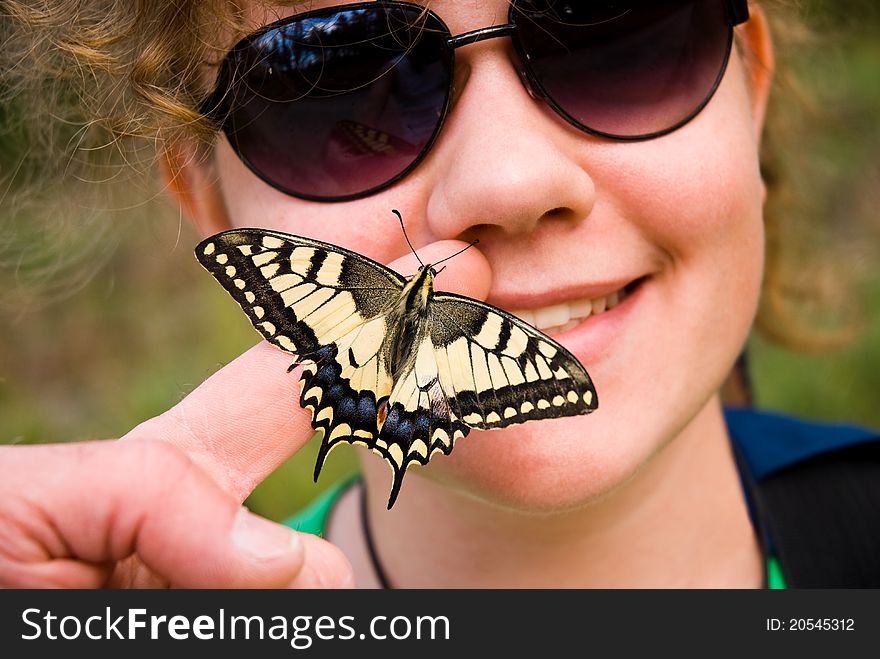 Butterfly sitting on a finger and girls face in the background. Butterfly sitting on a finger and girls face in the background