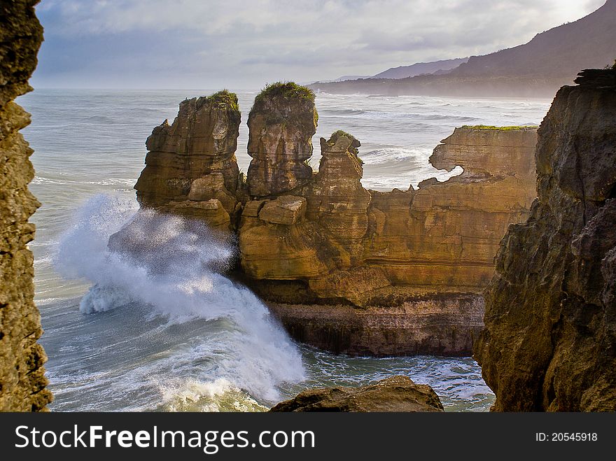 Incoming wave breaks against rocks with cat form. Incoming wave breaks against rocks with cat form.