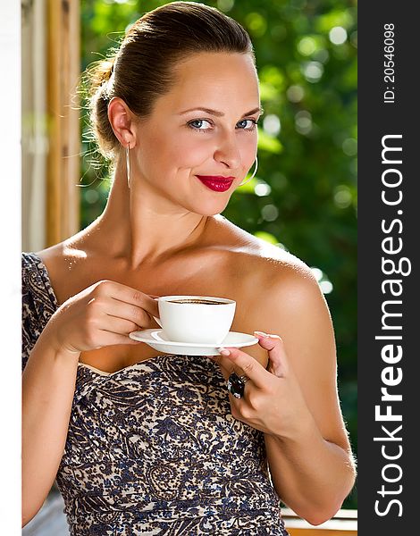 A young attractive woman with a cup of coffe near the window