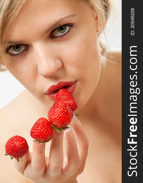 young woman with red strawberries picked on fingertips isolated on white background