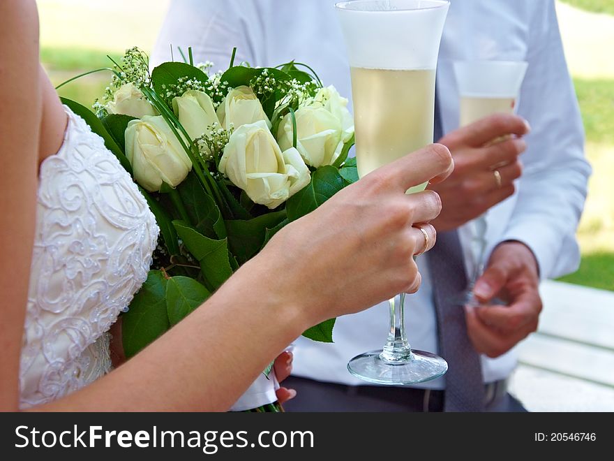 Bride and groom holding glasses of celebratory champagne and flowers. Bride and groom holding glasses of celebratory champagne and flowers