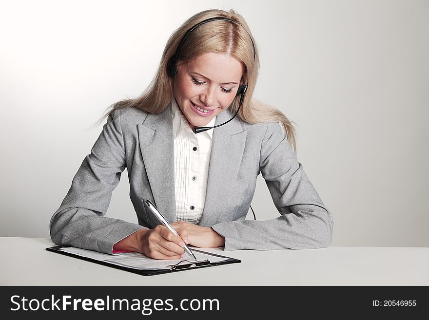 Business woman in a headset writing in notebook. Business woman in a headset writing in notebook